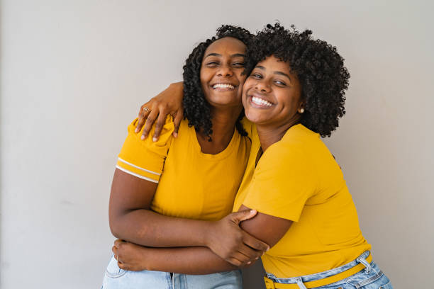 портрет двух сестер, обнимающихся друг с другом, улыбающихся - social awareness symbol фотографии стоковые фото и изображения