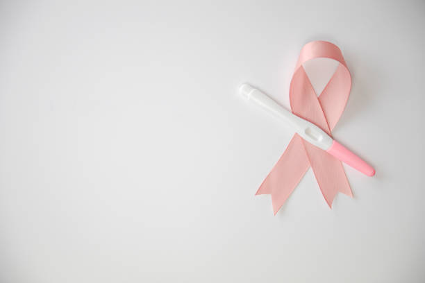 Pink satin breast cancer awareness ribbon with blank pregnancy test isolated on white background top view stock photo