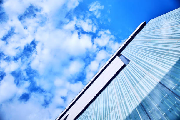 Underside angle view to perspective skyscraper contemporary glass building facade with cloudy blue sky background