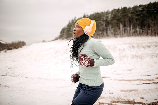 Young black woman doing a warm-up exercise in the snow