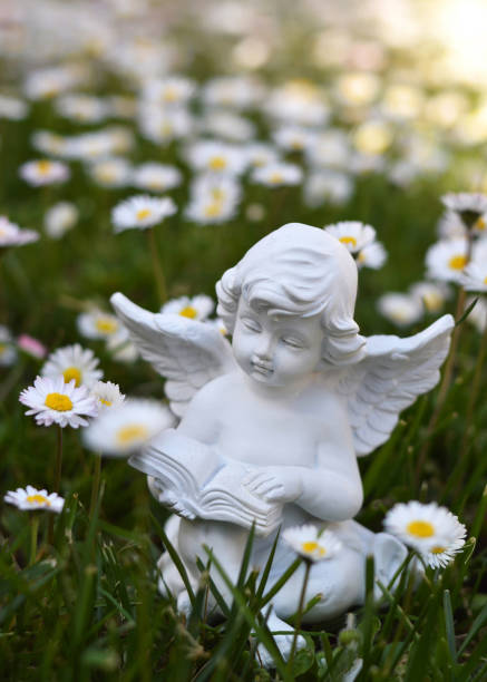 istock Angel sitting in the grass and reading a book 1359169760