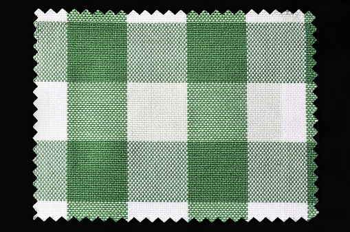 Green and white checkered fabric sample isolated on black background