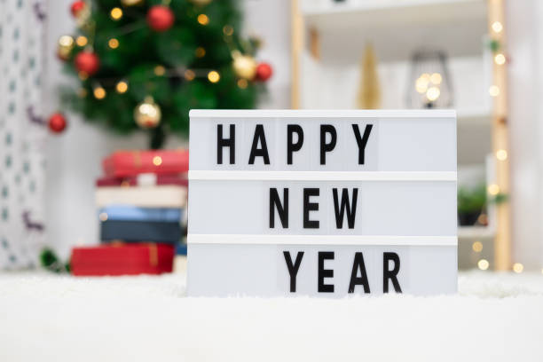 Happy New Year Lightbox on a fluffy white carpet with Christmas decorations on the background stock photo