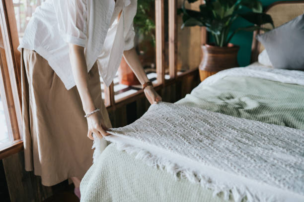 Cropped shot of young Asian woman doing her morning routine, making up her bed at home. Let's get the day started stock photo