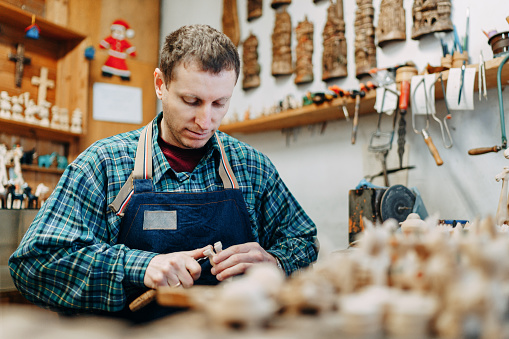 Skilled wood craftsman shaping small souvenirs in his workshop