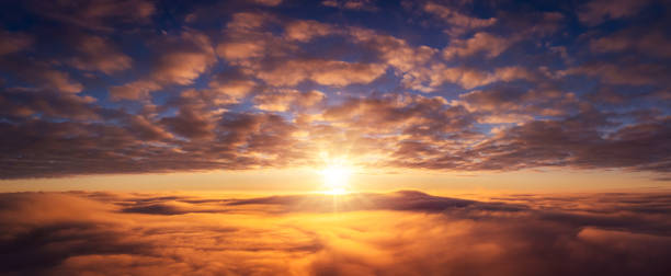 istock Wide panorama of setting sun above the clouds 1359174894