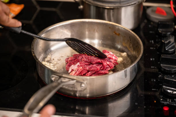 istock Hand using kitchen flipper frying sliced beef in iron pan on stove 1359176294