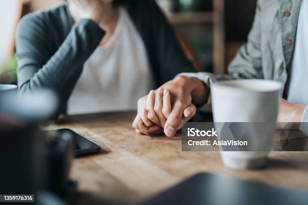 Close Up Of Young Asian Couple On A Date In Cafe Holding Hands On Coffee Table Two Cups Of Coffee And Smartphone On Wooden Table Love And Care Concept Stock Photo - Download Image Now