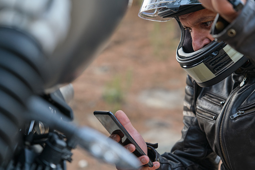 Close-up of a concerned motorcyclist calling the motorcycle insurance company