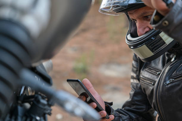 Worried motorcyclist calling motorcycle insurance with his cell phone stock photo