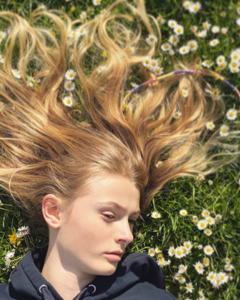 девушка, лежащая среди ромашек в траве - teenager adolescence portrait pensive стоковые фото и изображения