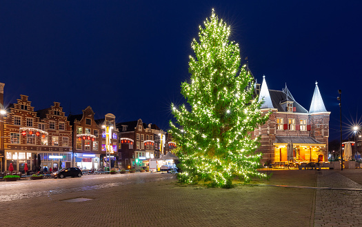 The building of the old medieval weighing chamber and the Christmas tree in the Nieuwmarkt square at night. Amsterdam. Netherlands.