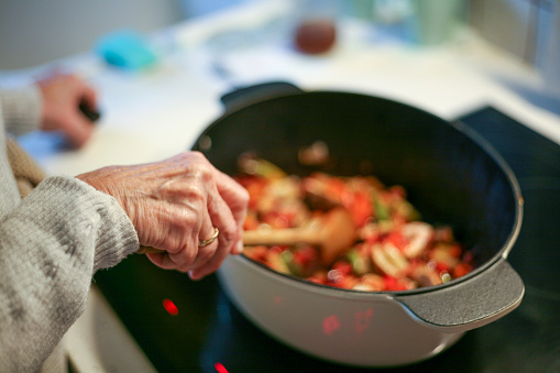 A woman cooking and stirring food in a roasting pan
