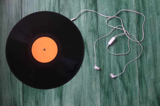 istock White headphones with wire and vinyl discs on an green background. Retro technique for playing music. 1359186769