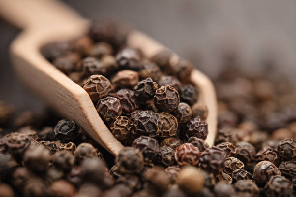 granos de pimienta negra en una cuchara de madera de cerca - spice condiment spoon wooden spoon fotografías e imágenes de stock