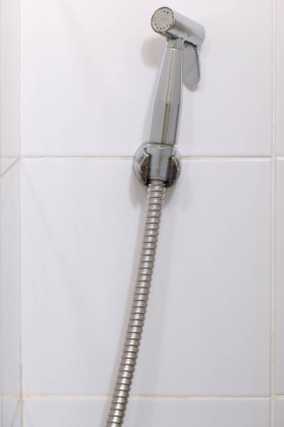 istock The modern bidet spray is hanging on the white tile wall. 1359187718