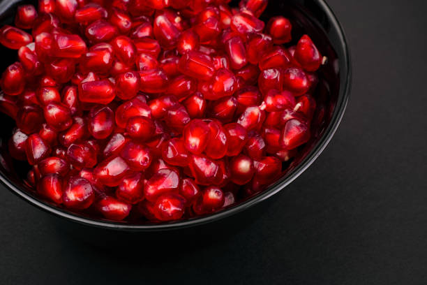 istock Ripe Pomegranate seeds in black bowl on black background 1359189083