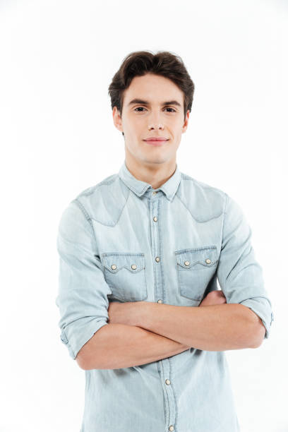 istock Young man standing with arms folded and looking at camera 1359190070