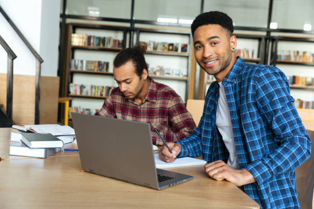 istock Young smiling african male student using laptop for a study 1359191281