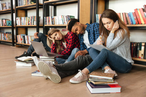 istock Young tired students sitting in library on floor 1359191656