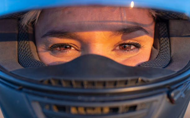 primer plano de los ojos marrones de una joven motera mirando a la cámara con un casco de seguridad negro - motorcycle women helmet sensuality fotografías e imágenes de stock