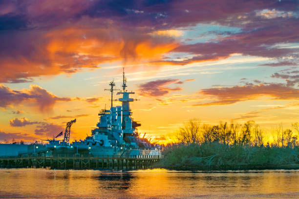 Battleship at Sunset The battleship USS North Carolina at sunset in Wilmington, NC. wilmington north carolina stock pictures, royalty-free photos & images