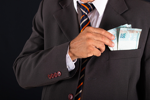 Business man holding Brazilian money in hand in his suit pocket.
