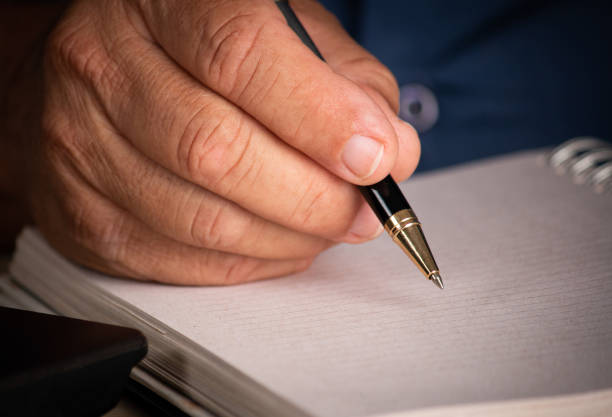 istock Male hand with pen signing on blank sheet 1359193519