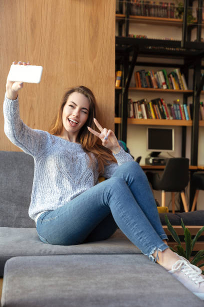 istock Smiling woman student sitting in library make selfie 1359193904