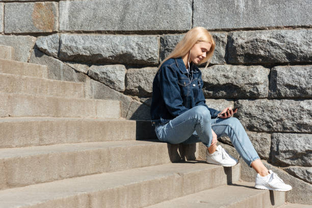 istock Blonde woman using smarthone and headphones 1359195846
