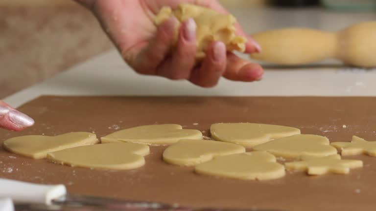 The woman works with the rolled dough. Cuts the dough into heart-shaped pieces. Prepares marshmallow sandwiches. Close-up shot.