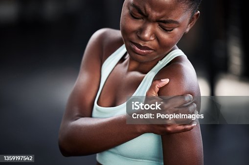 istock Shot of a young woman holding her shoulder in pain while at the gym 1359197542