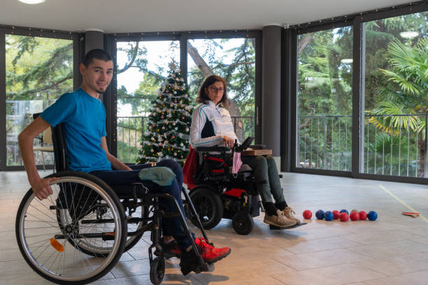 istock Two disabled people in wheelchairs play boccia next to a decorated Christmas tree with a beautiful view through the windows of the terrace of the green trees in the evil seaside resort. 1359197781