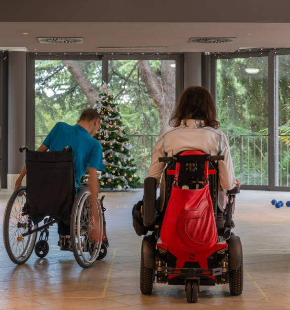 istock Two disabled people in wheelchairs play boccia next to a decorated Christmas tree with a beautiful view through the windows of the terrace of the green trees in the evil seaside resort. 1359198624