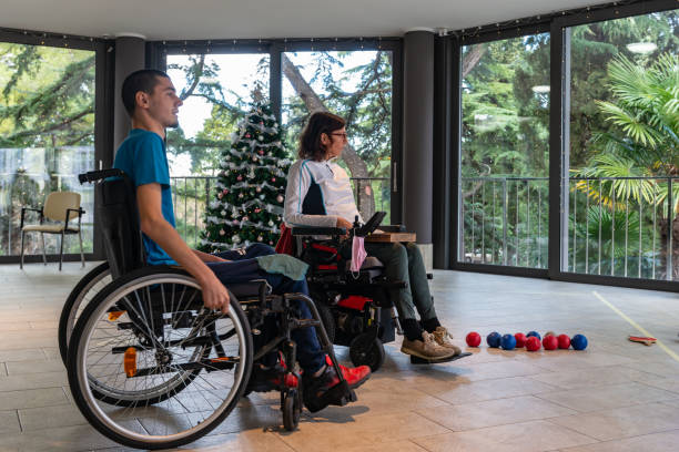 istock Two disabled people in wheelchairs play boccia next to a decorated Christmas tree with a beautiful view through the windows of the terrace of the green trees in the evil seaside resort. 1359198625