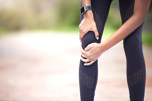 Closeup shot of an unrecognisable woman experiencing knee pain while exercising outdoors