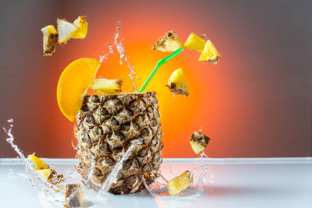 istock Pineapple cocktail. Pineapple with a straw. Flying pineapple slices and splashes. Citrus cocktail. 1359206027
