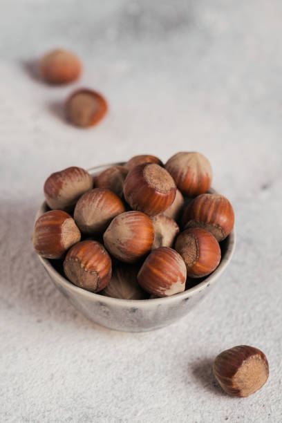istock Pile of hazelnuts filbert in a bowl on a white background. Fresh nuts in their shells. 1359206528