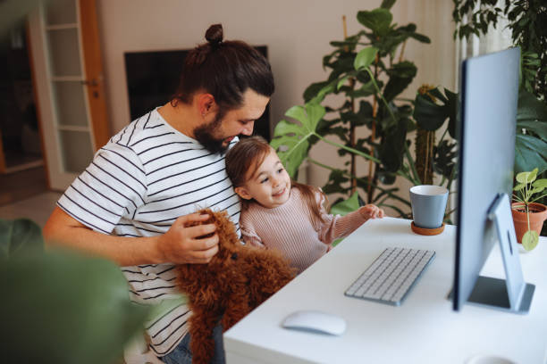 Father and daughter working together at home Having fun in dad's office  with red toy poodle. Little girl having fun while spending time in his dad's office.Father and daughter having fun working at home with children stock pictures, royalty-free photos & images