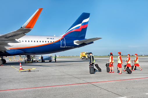 An aircraft crew, pilots and stewardesses in uniform going to the jet for departure: Abakan, Russia - August 08, 2020