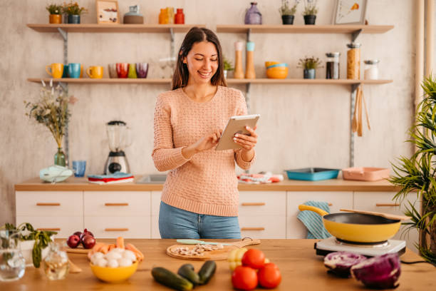 istock Woman looking for recipe on tablet while cooking 1359213237