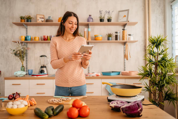 istock Woman looking for recipe on tablet while cooking 1359213280