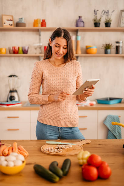 istock Woman looking for recipe on tablet while cooking 1359213315