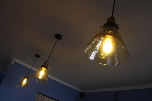 Close-up of incandescent light bulbs hanging in the dark room.  Decorative antique edison light bulbs with straight wire.