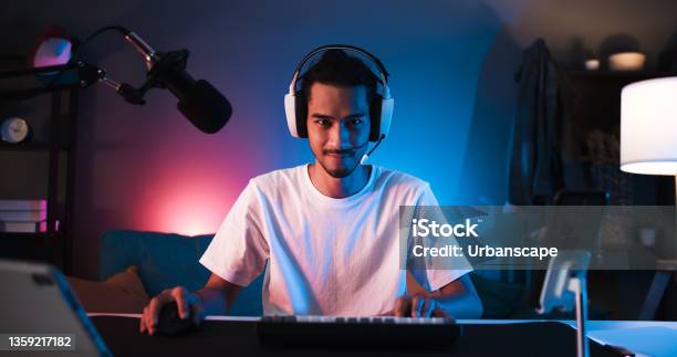 Young Confident Asian Man Playing Online Computer Video Game Colorful Lighting Broadcast Streaming Live At Home Gamer Lifestyle Esport Online Gaming Technology Concept Stock Photo - Download Image Now