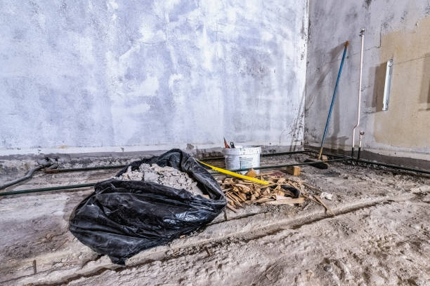 istock Construction waste debris in black plastic bag and wood chips on old concrete floor, from demolished room, broom, crowbar. Room corner, wide view 1359225098