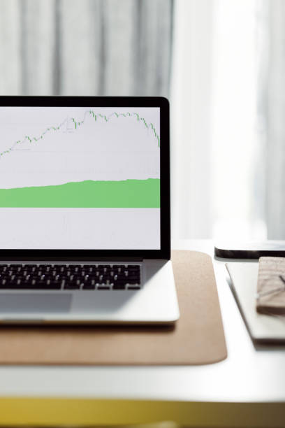 Close up photo of laptop computer screen with a increasing graph on a home office desk.