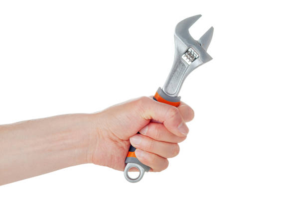 istock Bolt wrench, adjustable cap wrench in the hand of a worker, builder, isolated on a white 1359229054