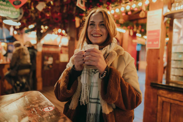 uśmiechnięta kobieta delektująca się grzaną winą na jarmarku bożonarodzeniowym - christmas market zdjęcia i obrazy z banku zdjęć