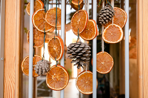 Handmade garland out of dried orange slices, pinecones on a glass door